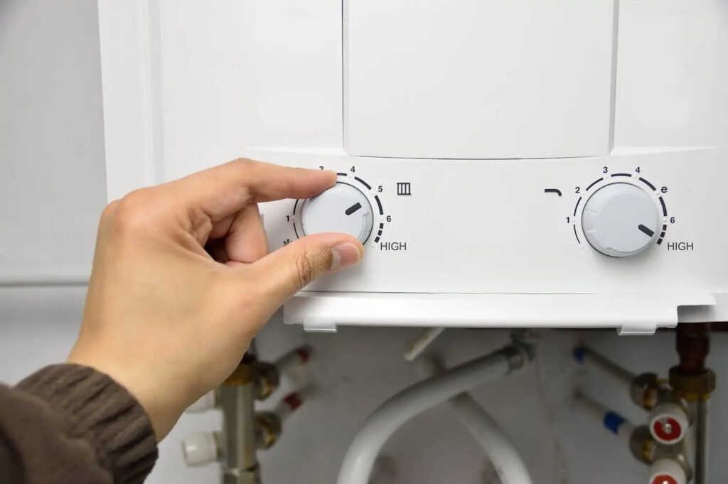 Person adjusting temperature dial on tankless water heater unit